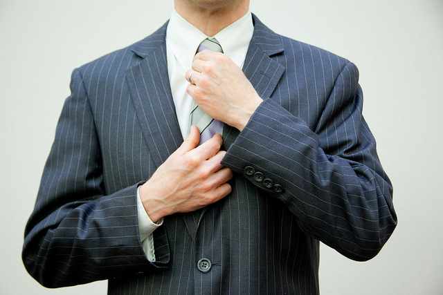 Mann im Anzug fasst sich an die Krawatte