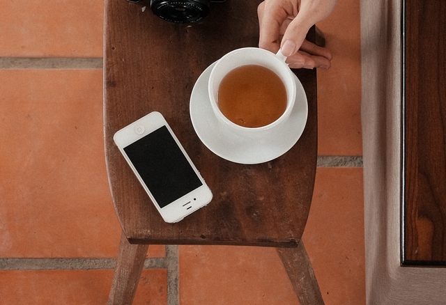 das sind ein smartphone und eine tasse tee auf einem tisch